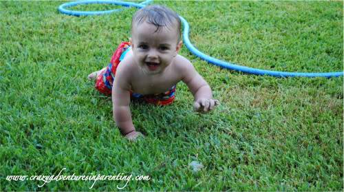 baby crawling through sprinkler