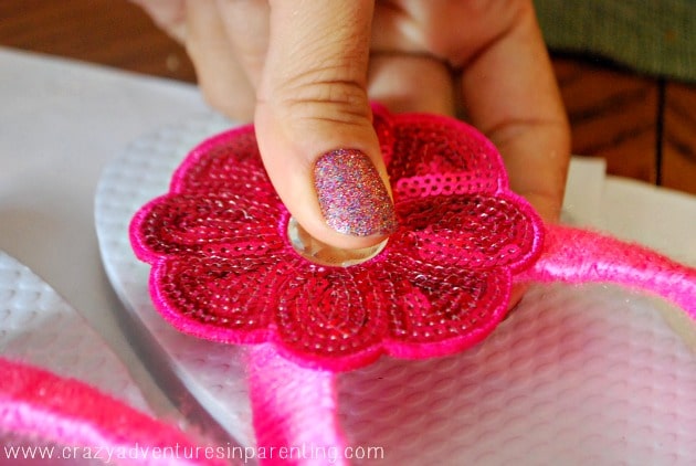 flower hot glued onto yarn tied flip flop