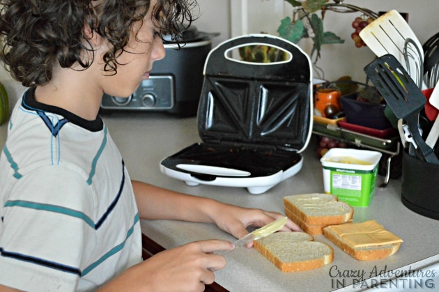 Preteen making grilled cheese on the sandwich maker