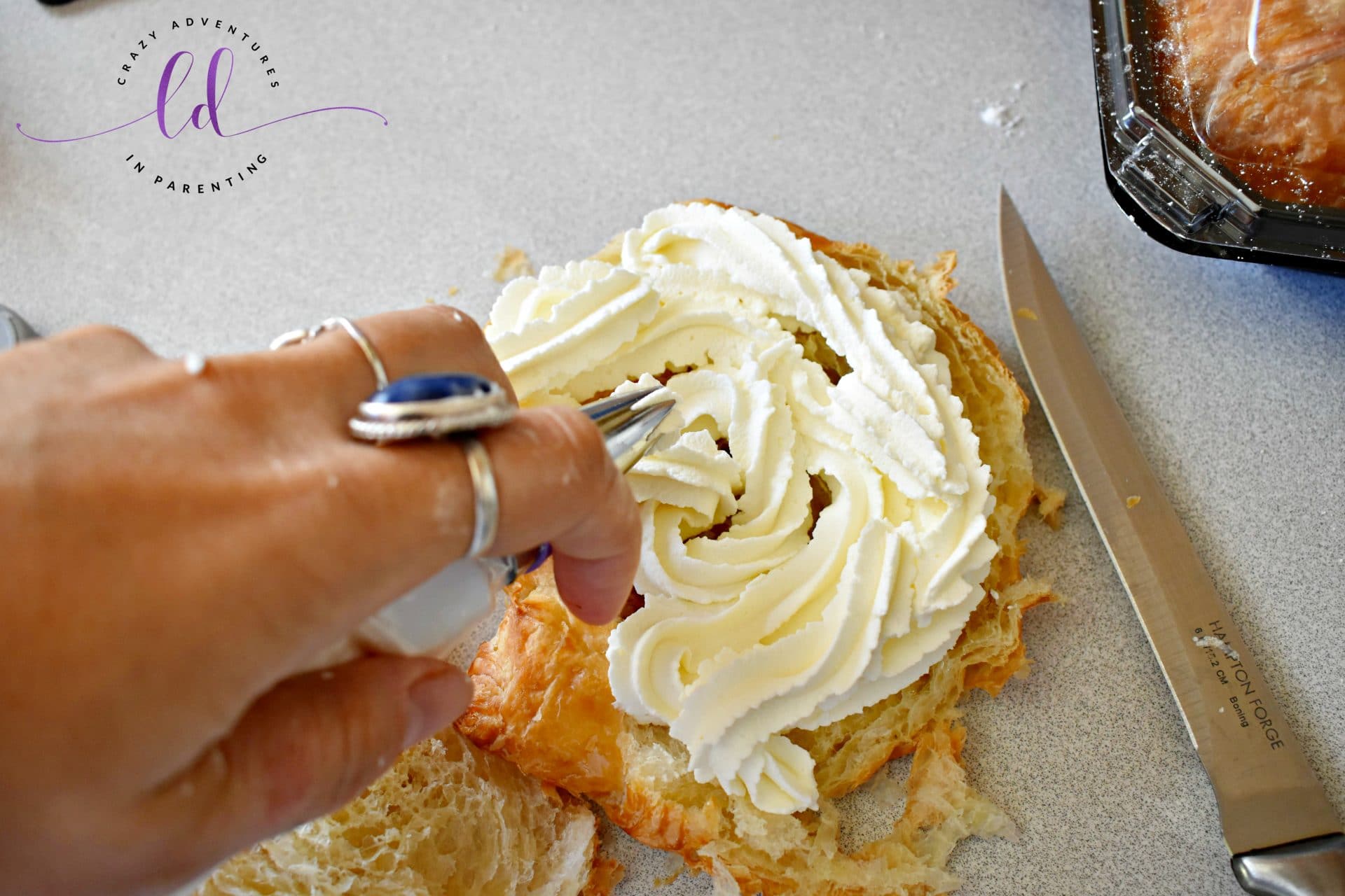 Piping homemade whipped cream into the Strawberry Shortcake Croissant