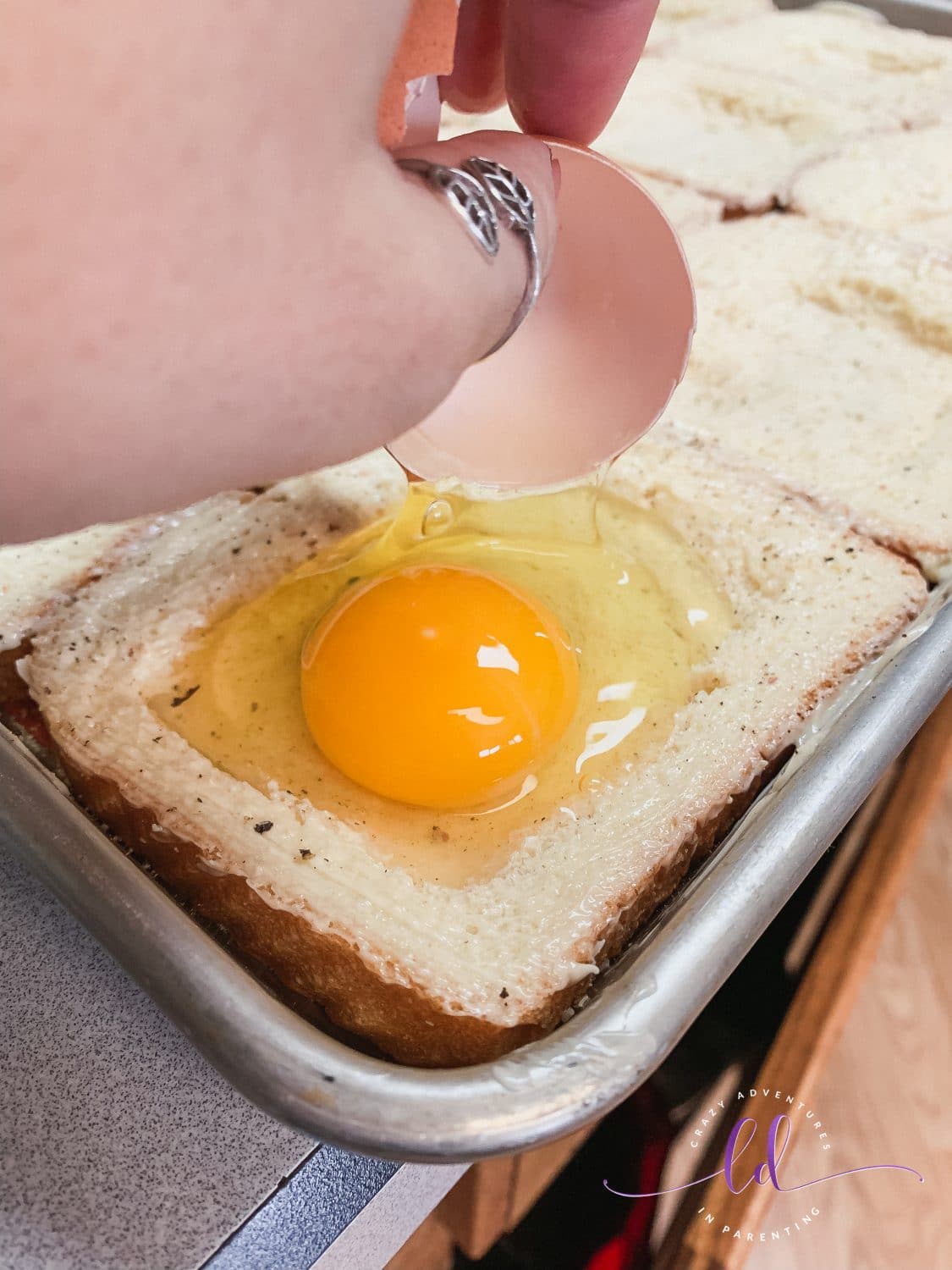 Cracking Eggs for Sheet Pan Cheesy Baked Egg Toast