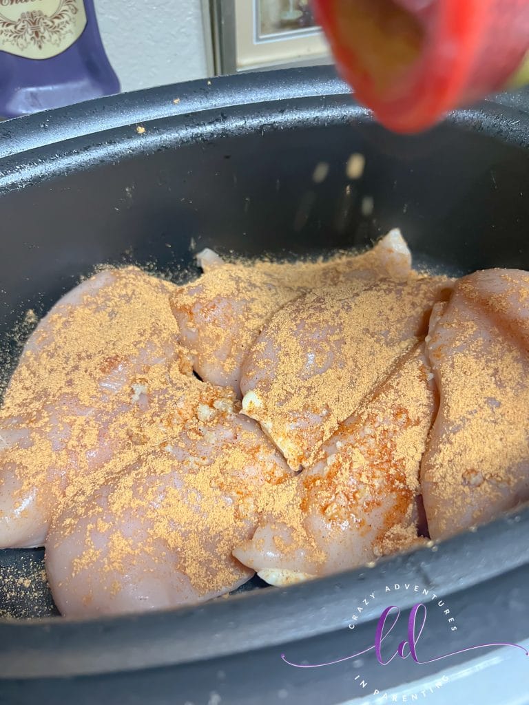 Add Taco Seasoning to Chicken Breasts in the pot to make Easy Creamy Chicken Tacos Recipe